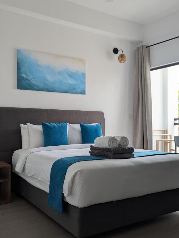 Double bed with blue cushions in a modern room at VillaBlu Dhiffushi